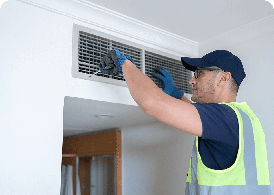 Technician inspecting air vent in ceiling.