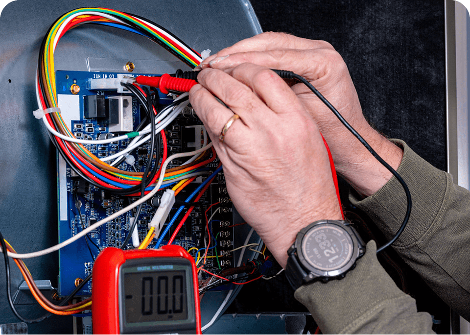 Hands testing circuit board with multimeter.