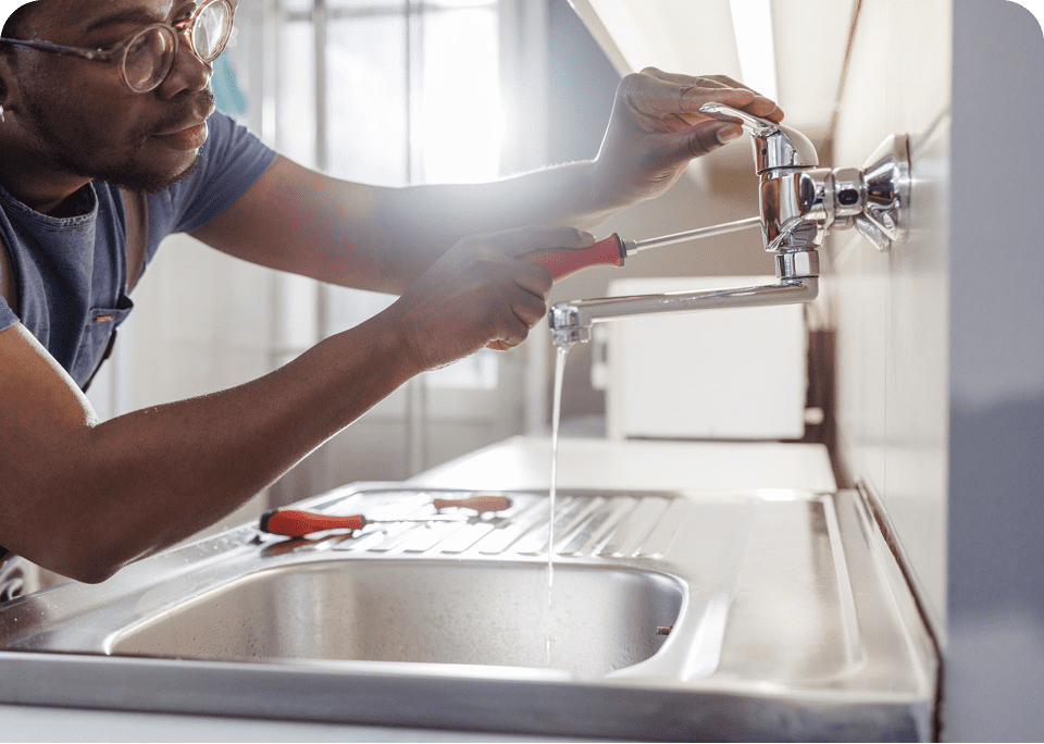 Person fixing kitchen sink with screwdriver.