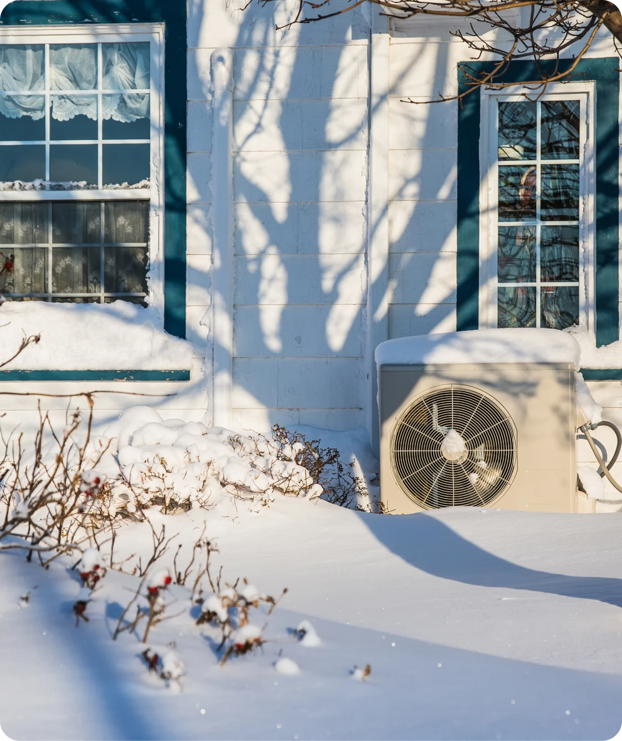 Snow-covered house with window and air conditioner.