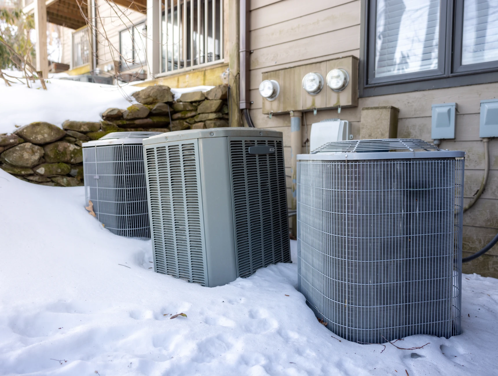 Air conditioning units covered with snow outdoors.
