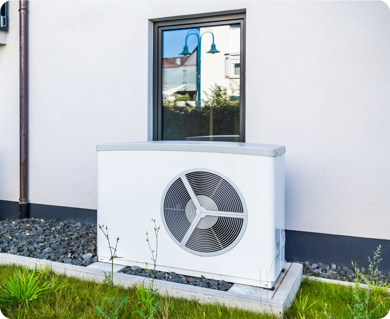 White outdoor heat pump unit by window.
